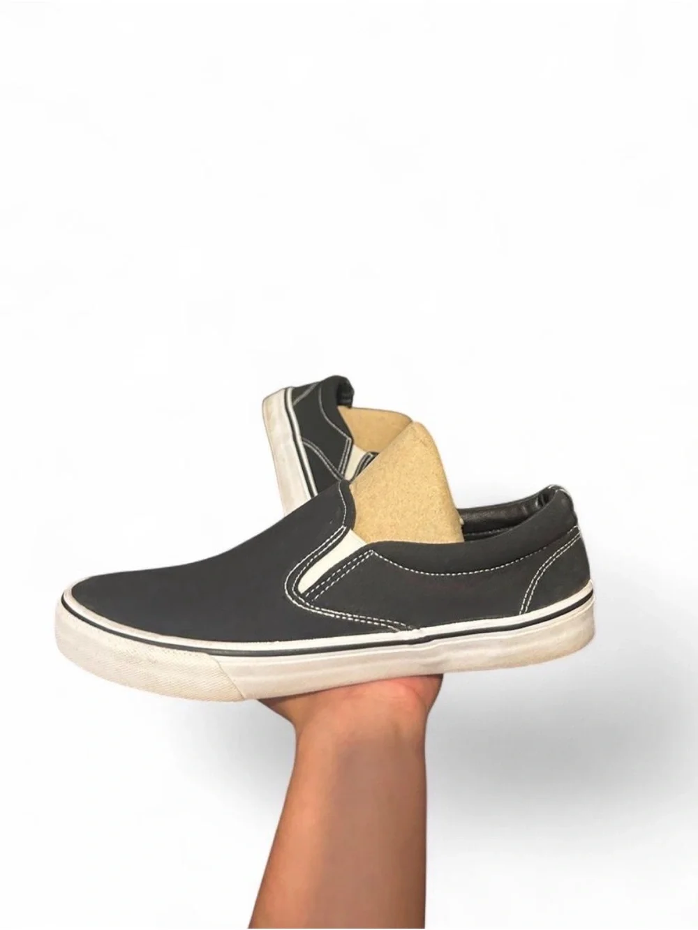Black slip-on sneakers with white sole and white stitching